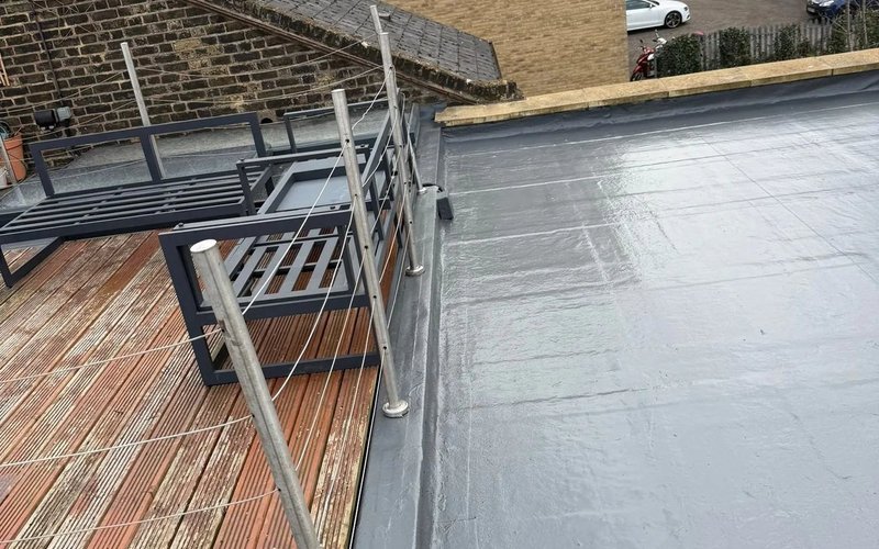 Completed dark grey flat roof surface with a raised perimeter kerb