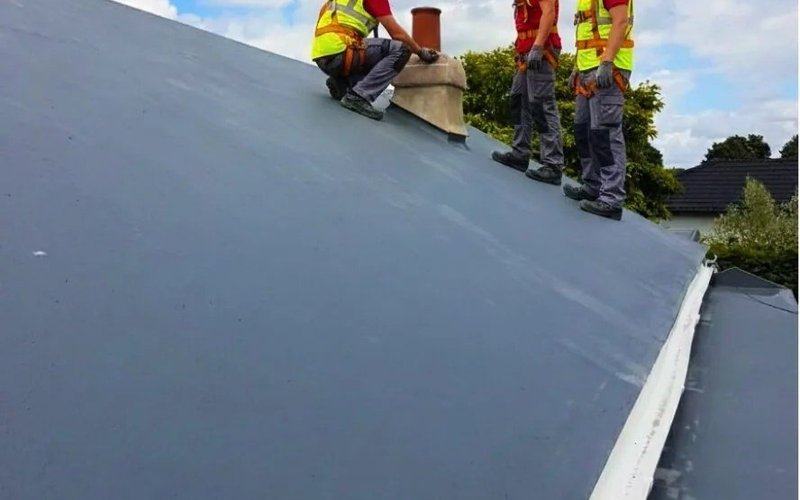 Roofing team working on a large waterproofed flat roof