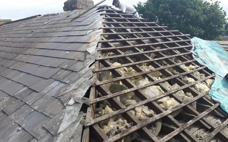 Partly stripped slate roof with exposed wooden battens during roof renewal