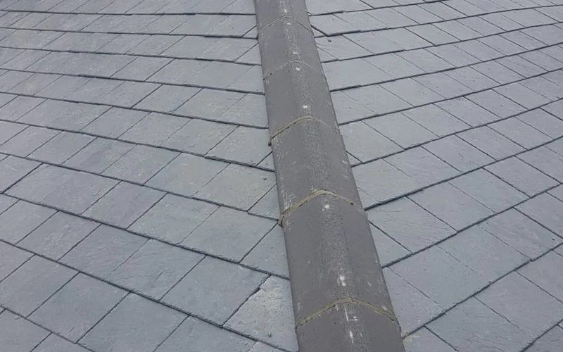Grey slate roof adjoining a brick chimney with lead flashing